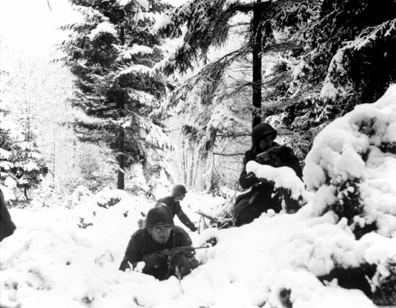 Soldats américains du 290e régiment d'infanterie combattant dans la neige durant la Bataille des Ardennes